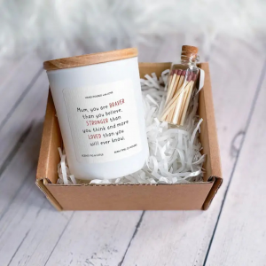 brave mum scented candle gift shown here laid in the gift box with the glass matches bottle next to it. The label reads. Mum you are braver than believe, stronger than you think and more loved than you will ever know.