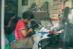 Conscious consumerism means knowing where your purchases come from. Woman working in a garment making workplace. Sat at a sewing machine